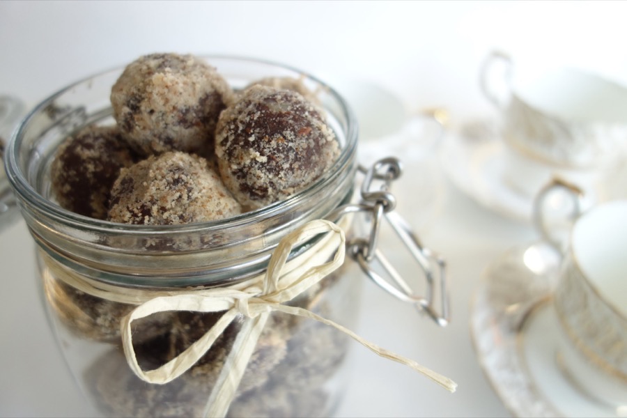 A glass jar of bliss balls beside porcelain teacups
